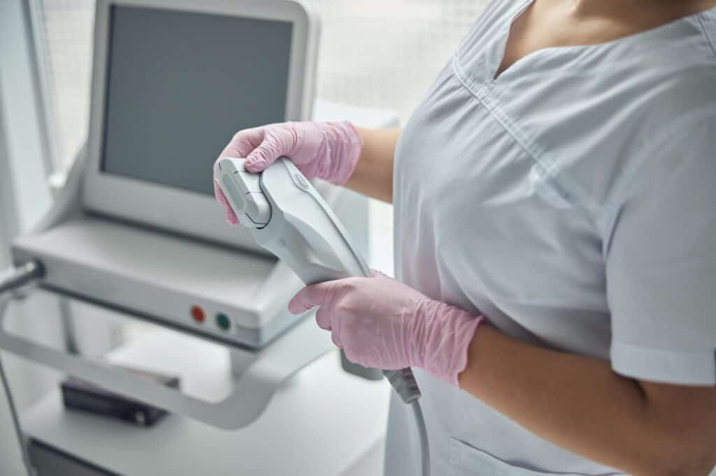 Young female beautician holding IPL laser device