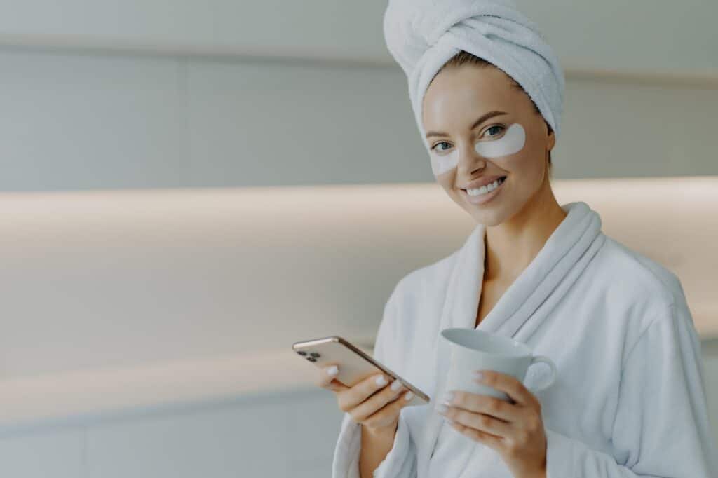 Glad beautiful woman with healthy skin cares about under eye skin applies moisturising patches