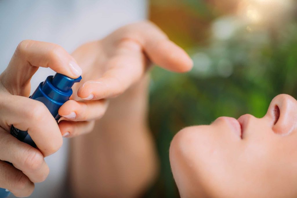 Retinol Treatment. Cosmetician Applying Retinol Serum on Woman’s Face