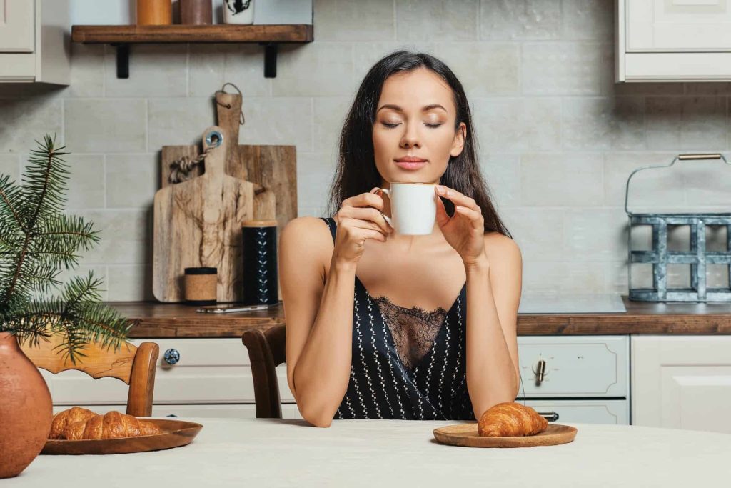 Sleepy mixed race woman drinking fresh coffe in the kitchen