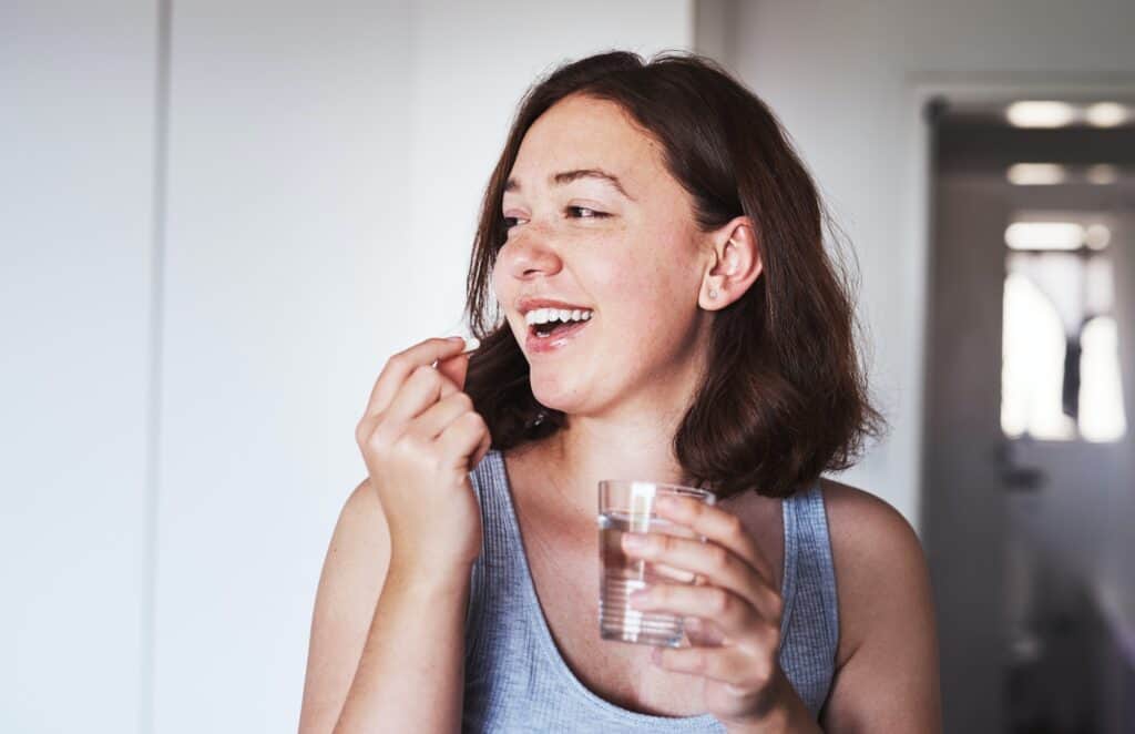 Do what it takes to maintain good health. cropped shot of a young woman taking medication at home.