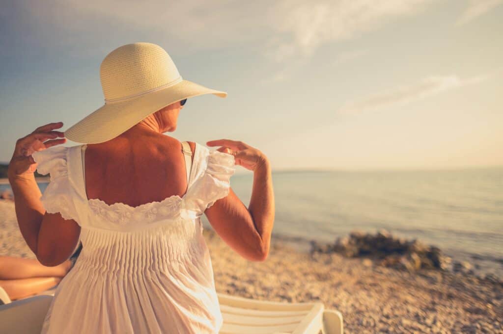 Retired Woman in Sun Protection Hat Relaxing on a Beach