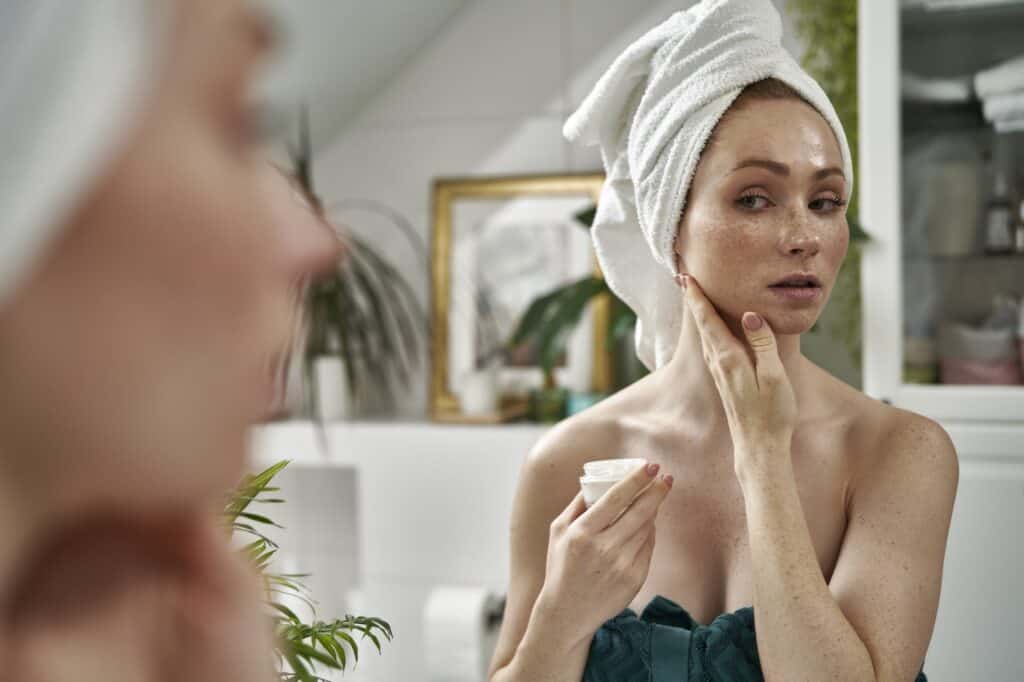 Woman using face cream after the shower in the bathroom
