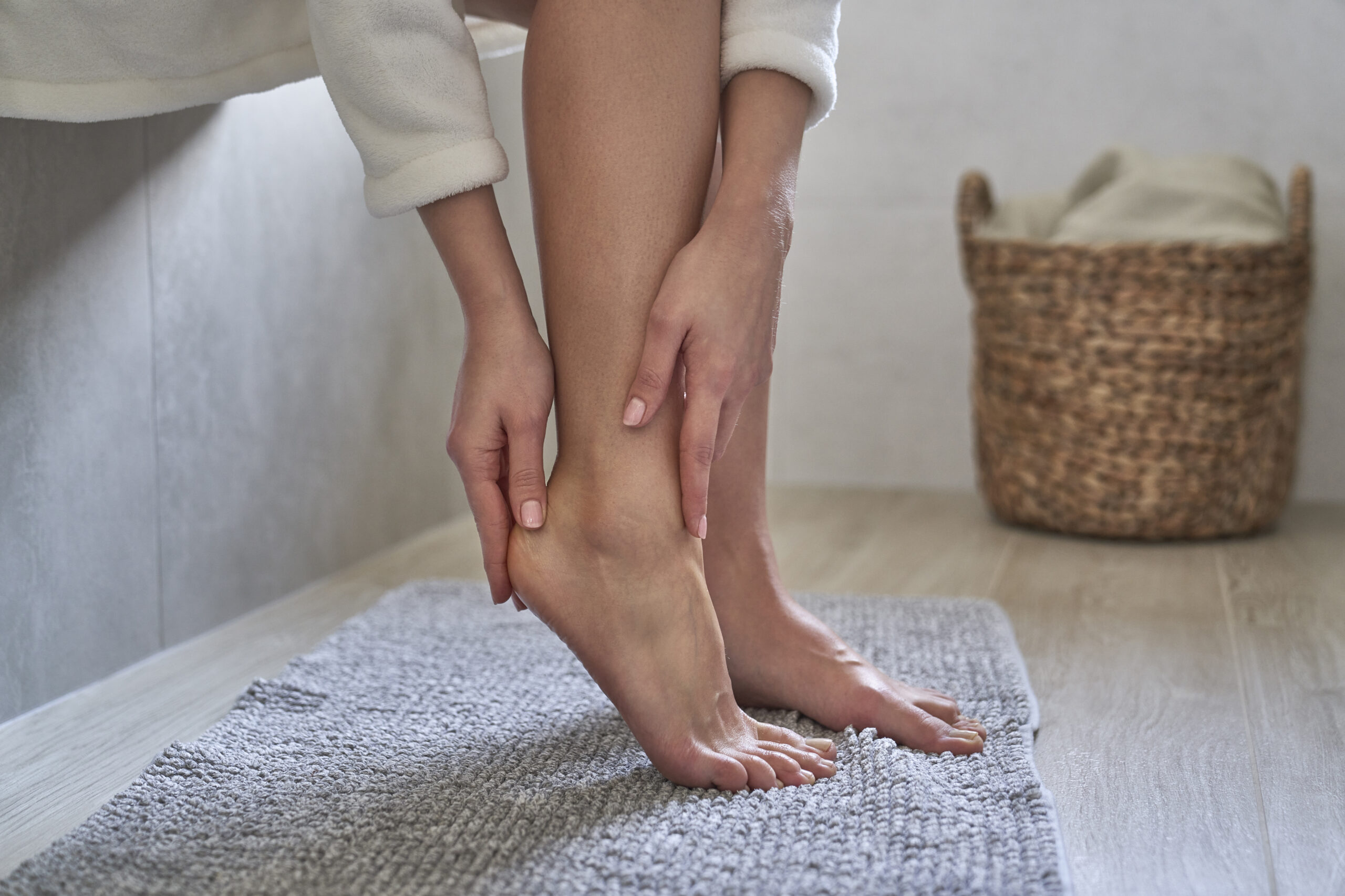 Caucasian woman in bathrobe applying moisturizing cream on heels