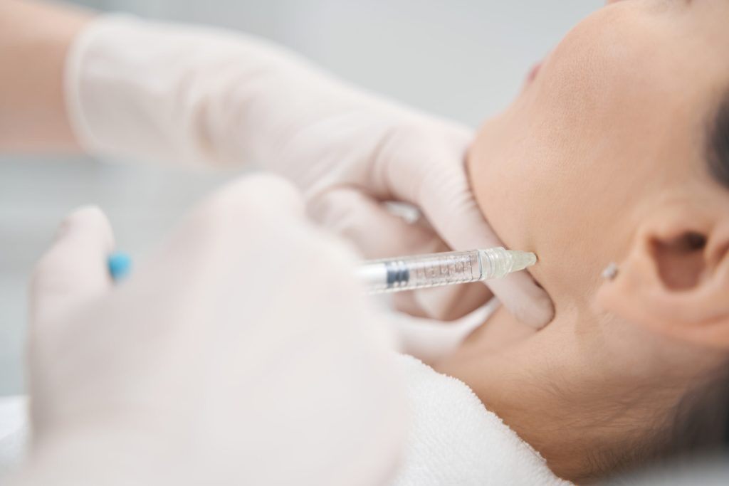 Woman receiving face lifting injection in beauty salon