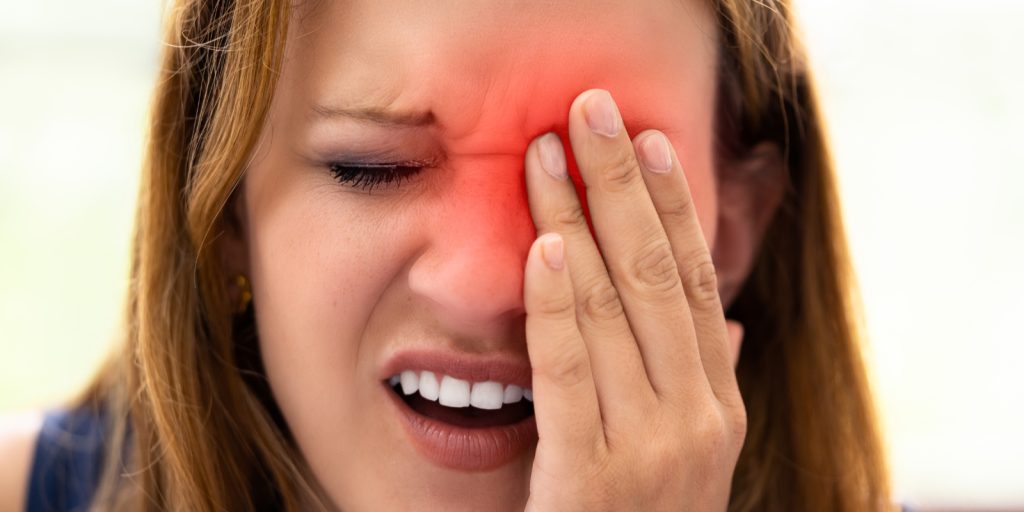 Dame som holder foran øyet sitt.