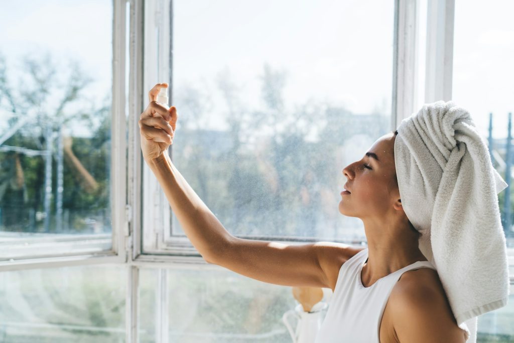 Relaxed woman spraying face mist