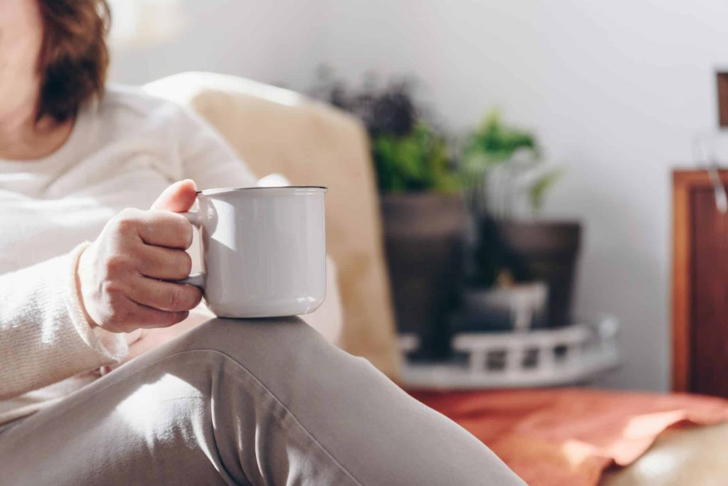 Close up of elderly woman hands while holding a cup of coffee