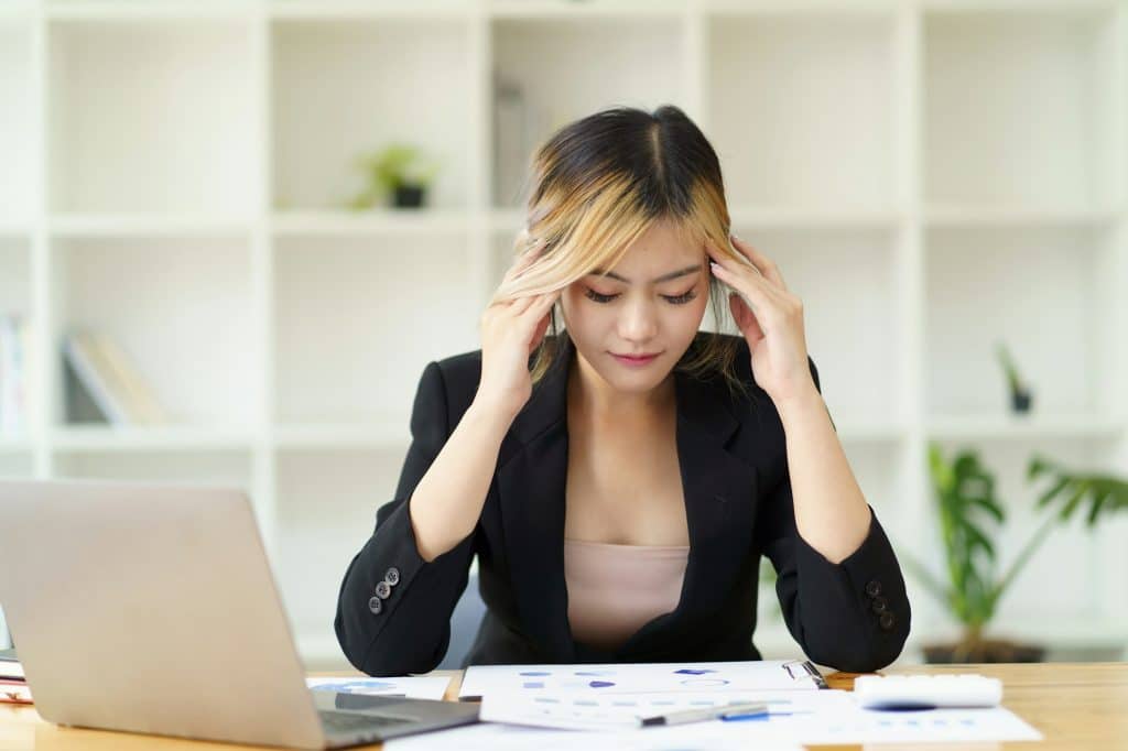 Tired Asian business woman suffering from dry eyes syndrome after long laptop use, exhausted female